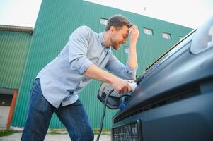 Smiling man unplugging the charger from the car photo