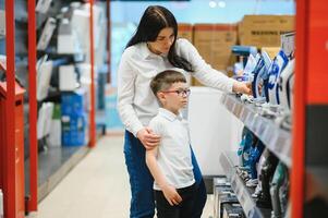 Woman with son choosing electric iron in electronics store photo