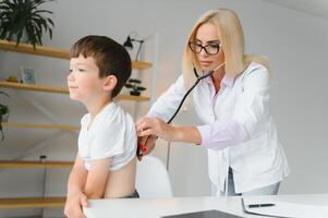 Pediatrician doctor examining little boy's heart beat and lungs to check for problems photo