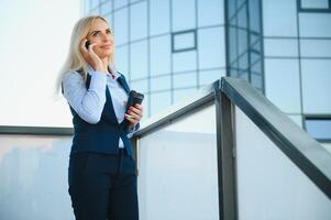 Beautiful Woman Going To Work With Coffee Walking Near Office Building. Portrait Of Successful Business Woman Holding Cup Of Hot Drink. photo