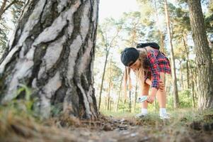 Image of cute kid with magnifying glass exploring the nature outdoors. Adorable little girl playing in the forest with magnifying glass. Curious child looking through magnifier on a sunny day in park. photo