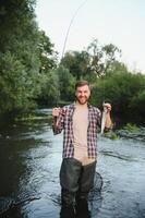 Fisherman hunting trouts in mountain river. Fishing net detail. photo