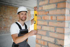 Man builder working in construction site. Male repairer in overall and helmet. photo