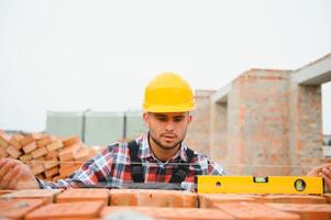 Installing brick wall. Construction worker in uniform and safety equipment have job on building photo