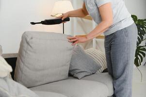 Portrait of senior woman with vacuum cleaner indoors at home, hoovering photo