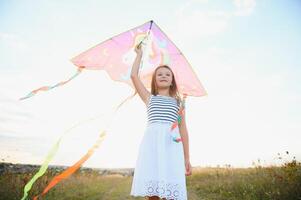 happy child girl with a kite running on meadow in summer in nature photo