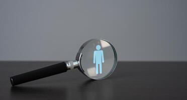 Symbol of a man in a magnifying glass. Finding people for work. Recruitment process, a search for workers to join a team or project. Quest for talent and unique qualities in candidates. photo