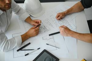 dos Ingenieria trabajando juntos y utilizando digital tableta mirando Plano y análisis con arquitectónico plan en escritorio foto