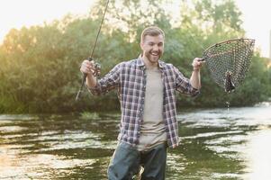 Fisherman catches a trout on the river in summer photo