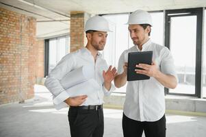 Two civil engineers or architects man inspecting construction of house. photo