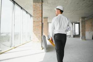 retrato de un arquitecto constructor estudiando diseño plan de el habitaciones, grave civil ingeniero trabajando con documentos en construcción sitio, edificio y hogar renovación, profesional capataz a trabajar. foto