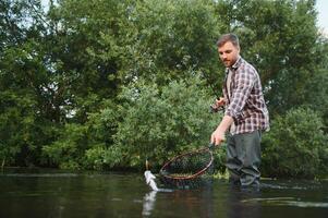 Fisherman picking up big rainbow trout from his fishing net photo