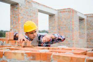 Busy with brick wall. Construction worker in uniform and safety equipment have job on building. photo