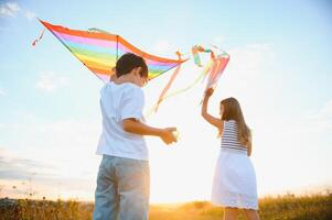 hermano y hermana jugando con cometa y avión a el campo en el puesta de sol. foto