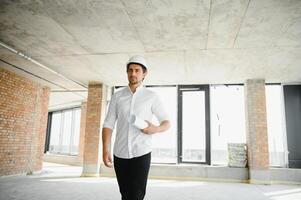 retrato de hombre arquitecto a edificio sitio. confidente construcción gerente vistiendo casco de seguridad. exitoso maduro civil ingeniero a construcción sitio con Copiar espacio. foto