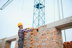 instalación de pared de ladrillo. trabajador de la construcción en uniforme y equipo de seguridad tiene trabajo en la construcción foto