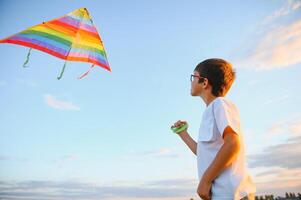 Boy is running with a kite during the day in the field photo