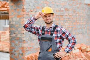 construction mason worker bricklayer installing red brick with trowel putty knife outdoors. photo