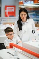 Beautiful young woman choosing which smart phone to buy. Shopping in tech store. photo