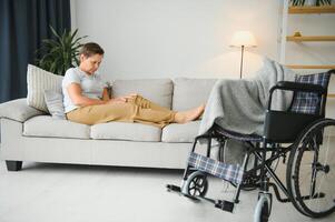 Brunette woman on couch near wheelchair photo