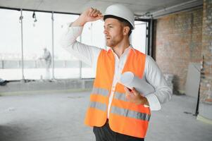 retrato de un arquitecto constructor estudiando diseño plan de el habitaciones, grave civil ingeniero trabajando con documentos en construcción sitio, edificio y hogar renovación, profesional capataz a trabajar. foto