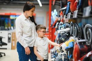 Mother and son shopping for electric vacuum cleaner, smiling photo