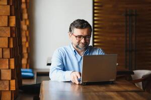 negocio, tecnología y personas concepto , mayor empresario con ordenador portátil computadora Bebiendo café a moderno cafetería. foto