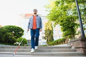 Blind Man Walking On Sidewalk Holding Stick photo