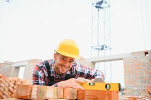 amarillo de colores difícil sombrero. joven hombre trabajando en uniforme a construcción a tiempo de día. foto