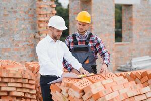 engineer and builder in hard hats discussing blueprint on construction site. photo