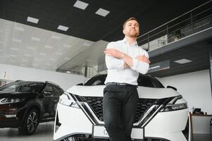 Young handsome man at show room standing near car photo