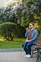 Young blinded man using phone and sending voice message photo