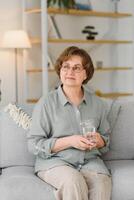 age, health care and people concept - happy senior woman with glass of water at home photo