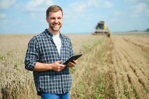 Farmer Standing In Wheat Field At Harvest photo