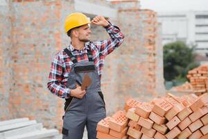 construcción masón trabajador albañil instalando rojo ladrillo con paleta masilla cuchillo al aire libre. foto