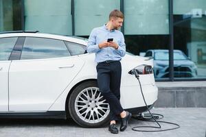 Man charges an electric car at the charging station photo