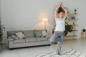 de edad mediana mujer haciendo yoga a hogar para extensión y siendo saludable. foto