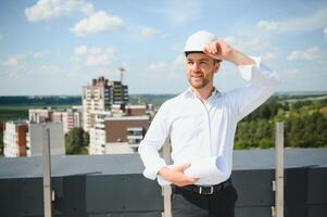 Portrait of man architect at building site. Confident construction manager wearing hardhat. Successful mature civil engineer at construction site with copy space. photo