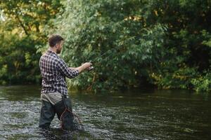 Fisherman catches a trout on the river in summer photo