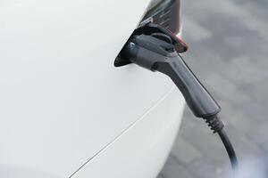 Close up of the Hybrid car electric charger station with power supply plugged into an electric car being charged. photo