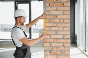 Portrait of handsome male builder in overalls and hard hat photo