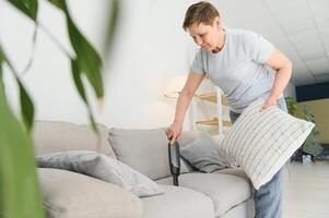 Portrait of senior woman with vacuum cleaner indoors at home, hoovering photo