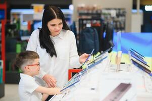 Beautiful young woman choosing which smart phone to buy. Shopping in tech store. photo