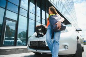 Woman charging electro car at the electric gas station photo