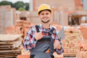 construction mason worker bricklayer installing red brick with trowel putty knife outdoors. photo