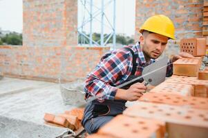 Busy with brick wall. Construction worker in uniform and safety equipment have job on building. photo