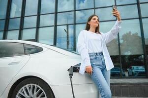 eléctrico coche cargando en calle. ecológico coche conectado y cargando pilas niña esperando poder suministro conectar a eléctrico vehículos para cargando foto