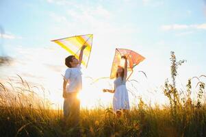 Brother and sister playing with kite and plane at the field on the sunset. photo