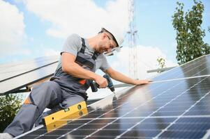 Male worker with solar batteries. Man in a protective helmet. Installing stand-alone solar panel system photo