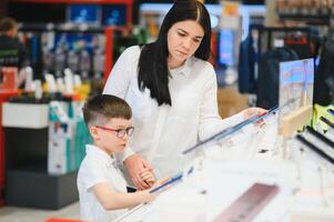 Beautiful young woman choosing which smart phone to buy. Shopping in tech store. photo